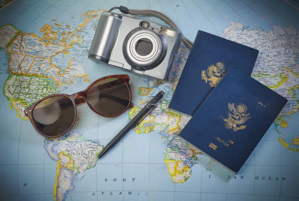A digital camera, two U.S. passports, sunglasses, and a pen rest on a world map.